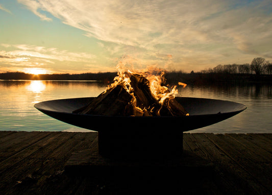 Asia Series oriental steel fire pit burning wood on a lakeside dock.