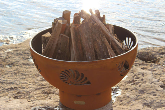 The BeachComber Fire Pit, displayed on the lake shore, full of fire wood.