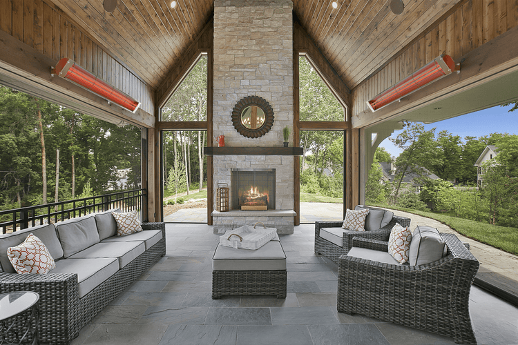Outdoor patio with wicker furniture, fireplace, and scenic view using the Bromic Cobalt Electric Patio Heater.