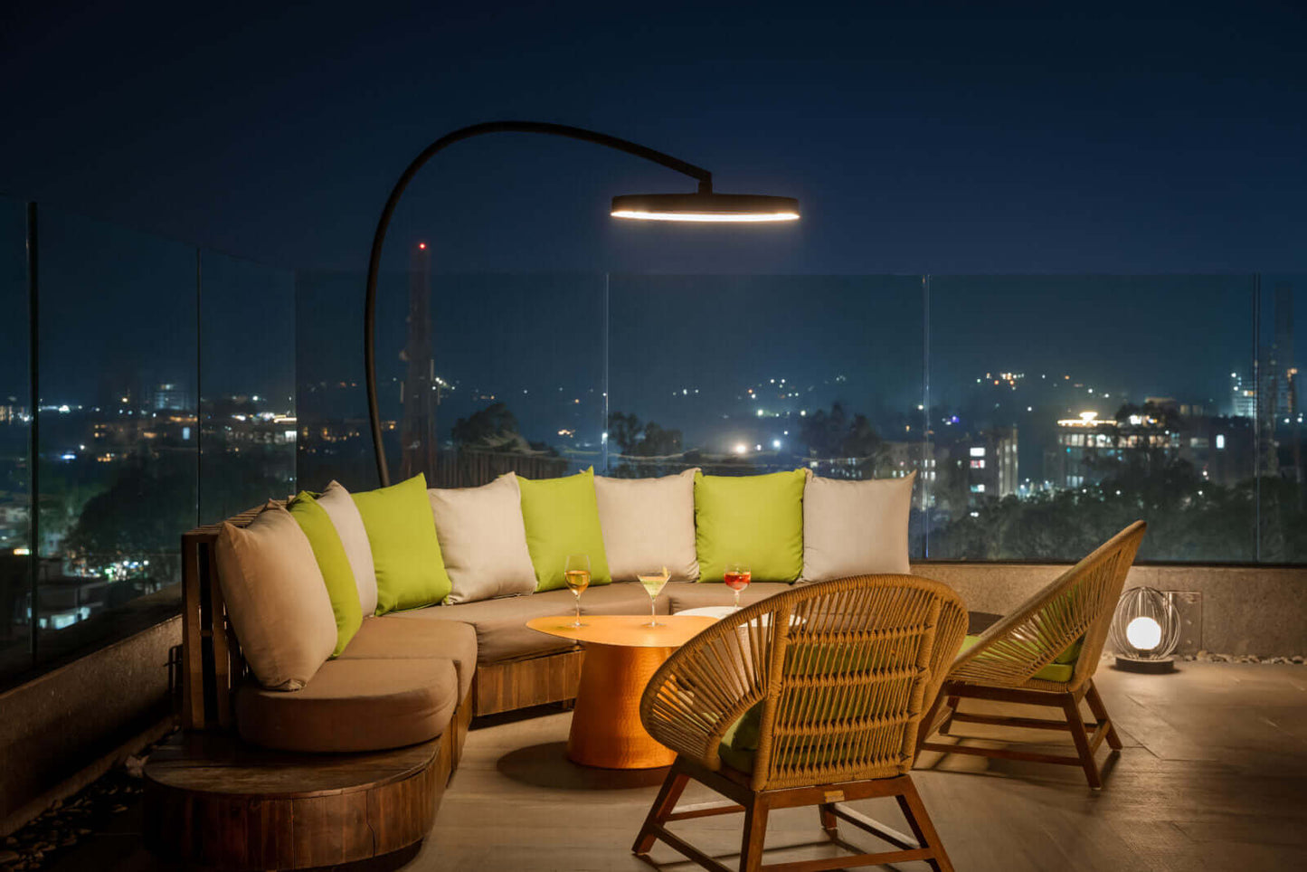 Outdoor evening setting with a sofa, chairs, and table on a rooftop with city lights in the background, using the Modern Black Bromic Portable Outdoor Heater.