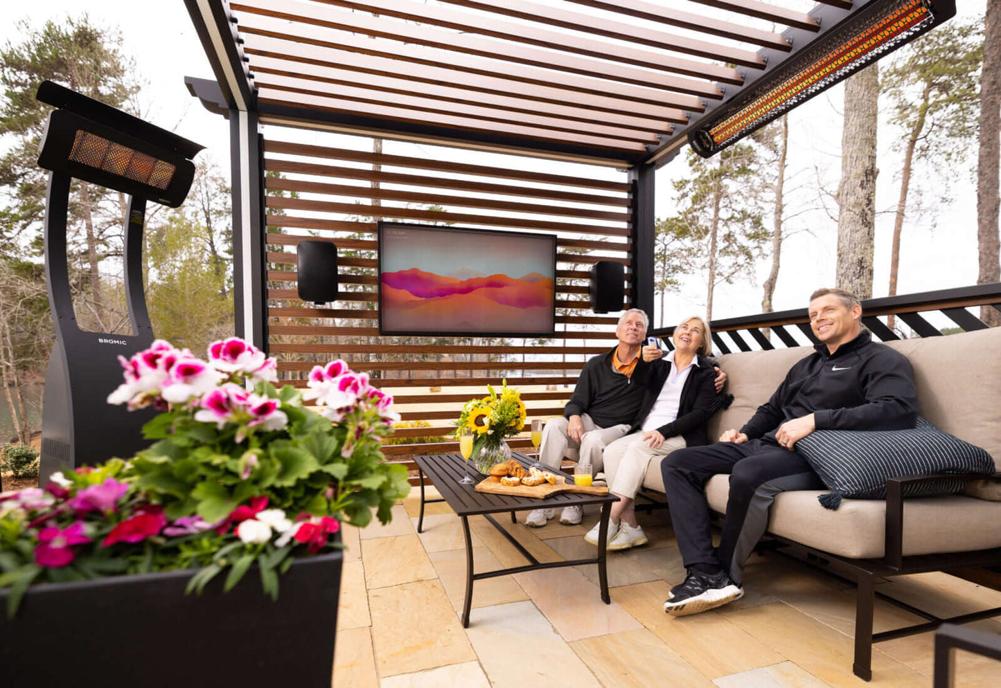 People sitting on a patio with outdoor furniture and heaters, enjoying a scenic view.