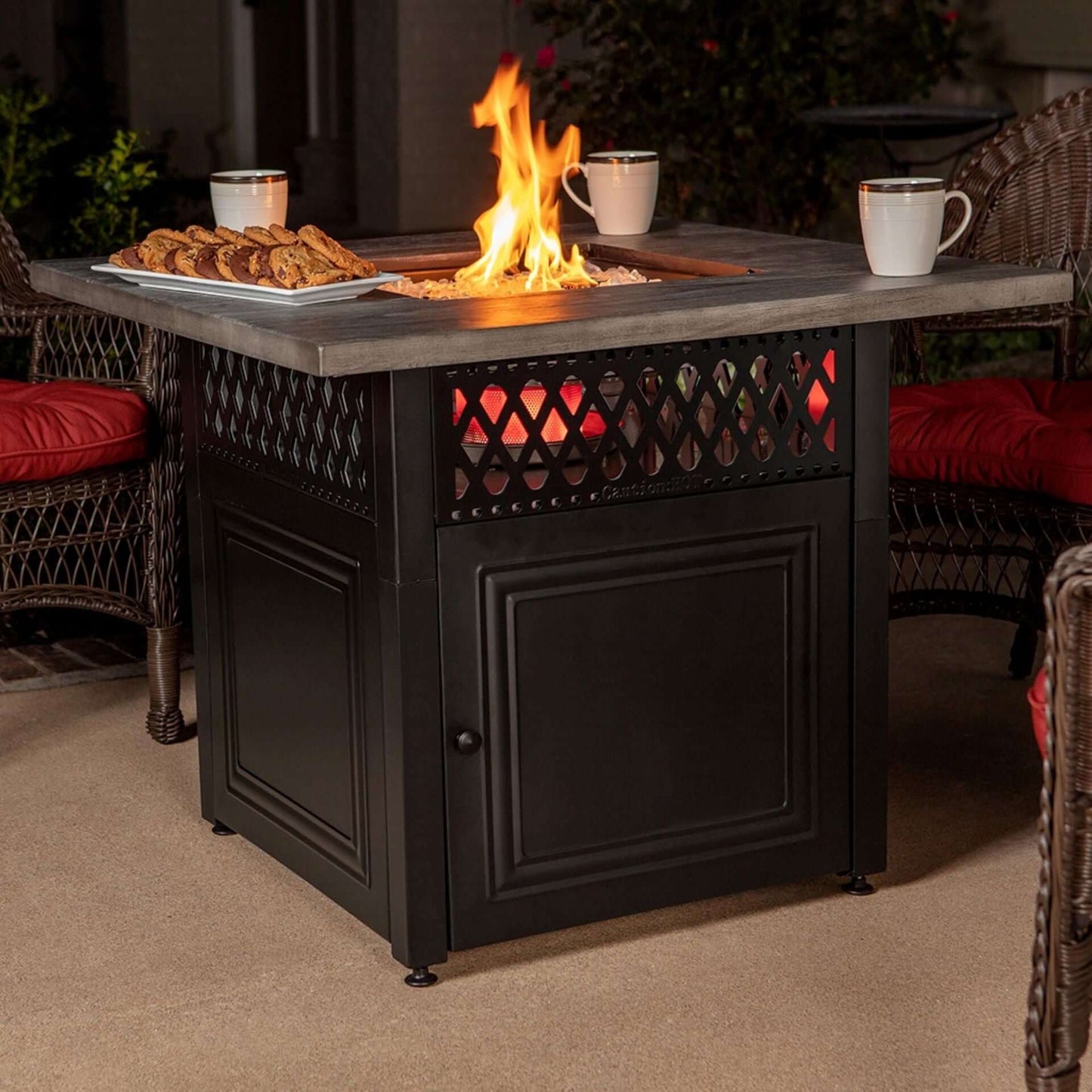 The award winning Dakota Dual Heat Gas outdoor firepit, displayed on a outdoor patio with a warm flame, surrounded by chairs.