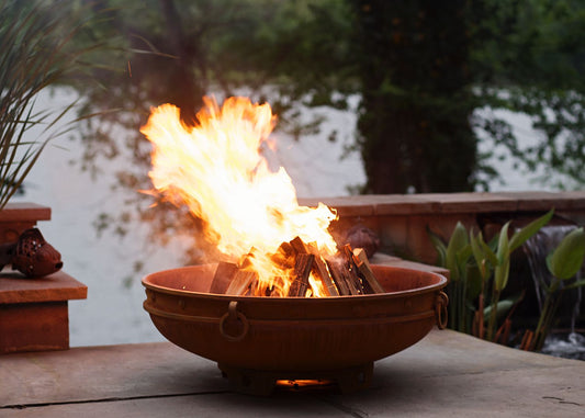 The Emperor Fire Pit, shown on an outdoor patio, with a huge warm flame.