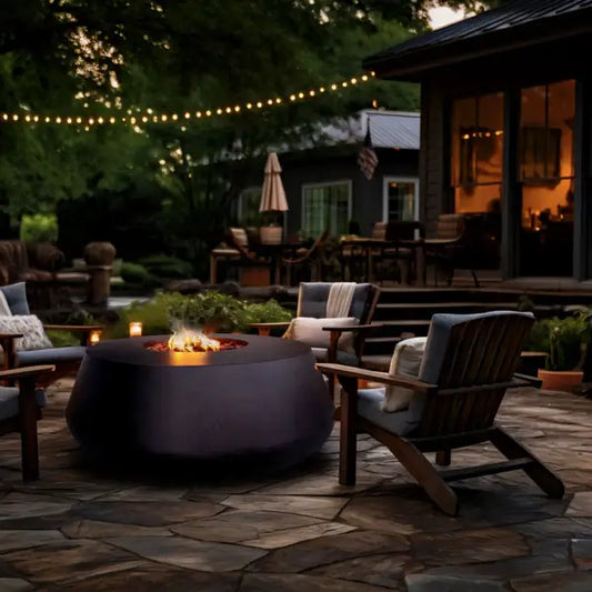 The Indiana Modern Fire Pit 03 in the Noir color option, displayed on a back yard patio, with a warm roaring flame.