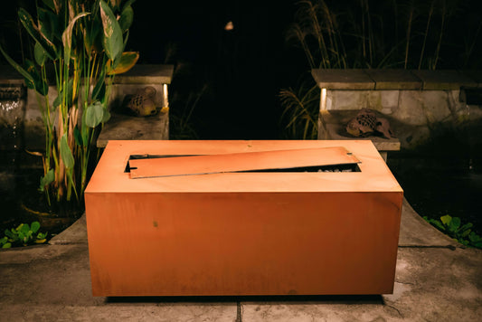 The hand crafted Linear Series Fire Pit, displayed on a cozy backyard patio.