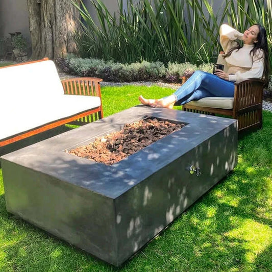 The beautiful Manhattan Concrete Fire Pit, Displayed in the Graphite color option, in a backyard garden.