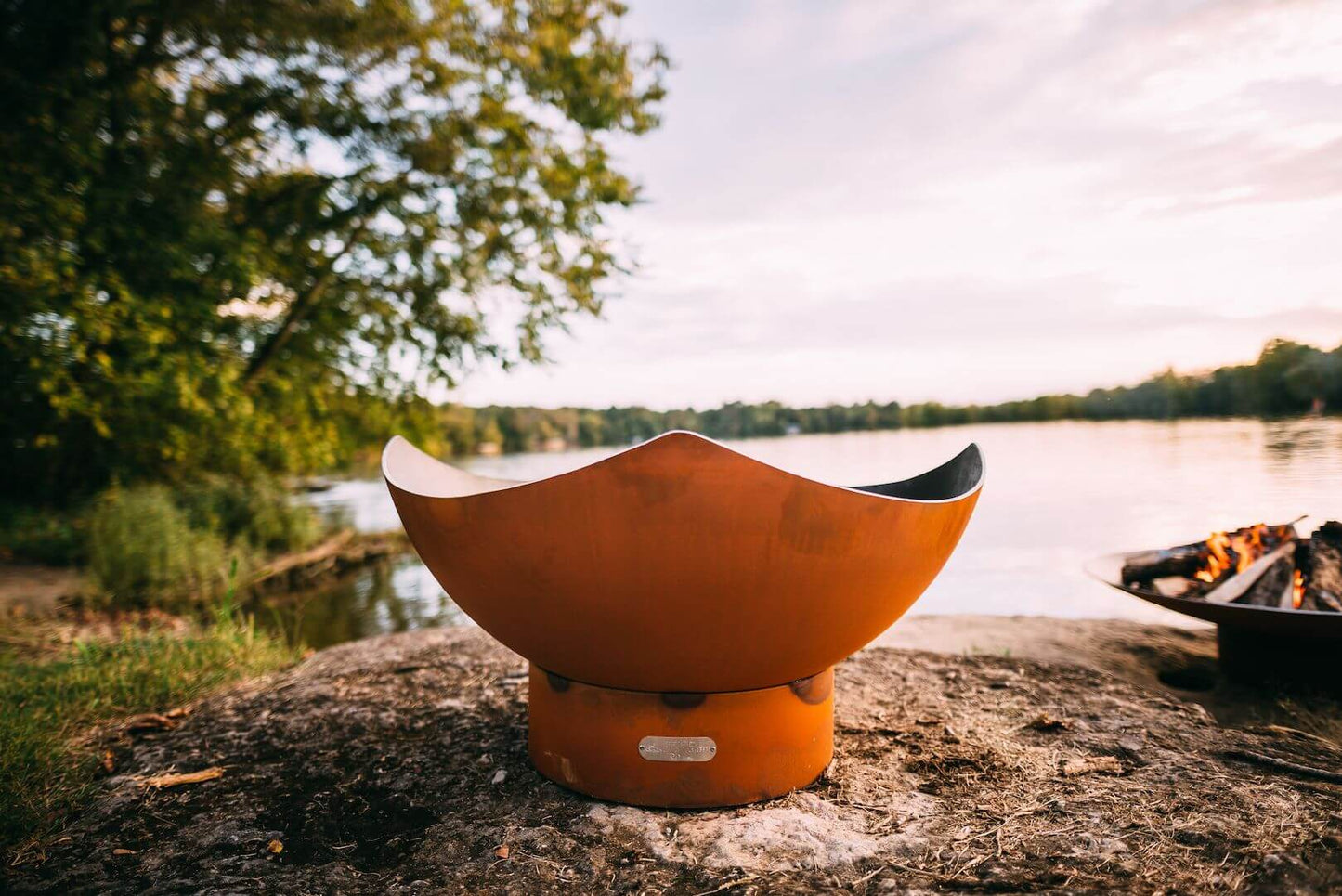 The elegant Manta Ray Fire Pit displayed on the lakeside shore.