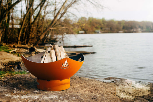 The gorgeous Namaste Fire Pit, Displayed on the lakeside rock, full of wood ready to be used.
