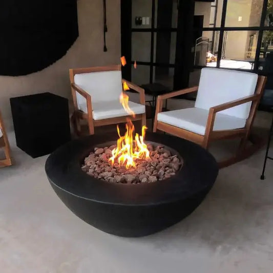 The Venecia Concrete Fire Bowl, Displayed in the Noir color option ona backyard patio.