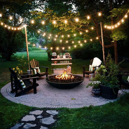 The Venecia Concrete Fire Bowl 06, Displayed in the Noir color option in a backyard garden.