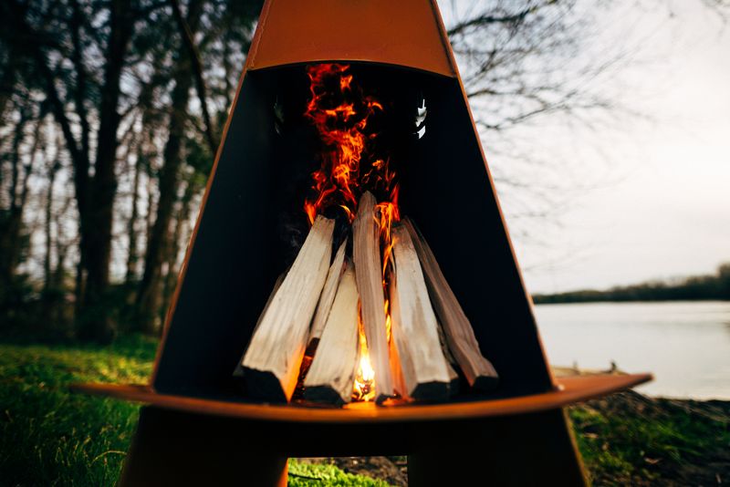 The Vesuvius wood burning fire pit, Displayed in a up close image, showing its beautiful design, with a warm flame.