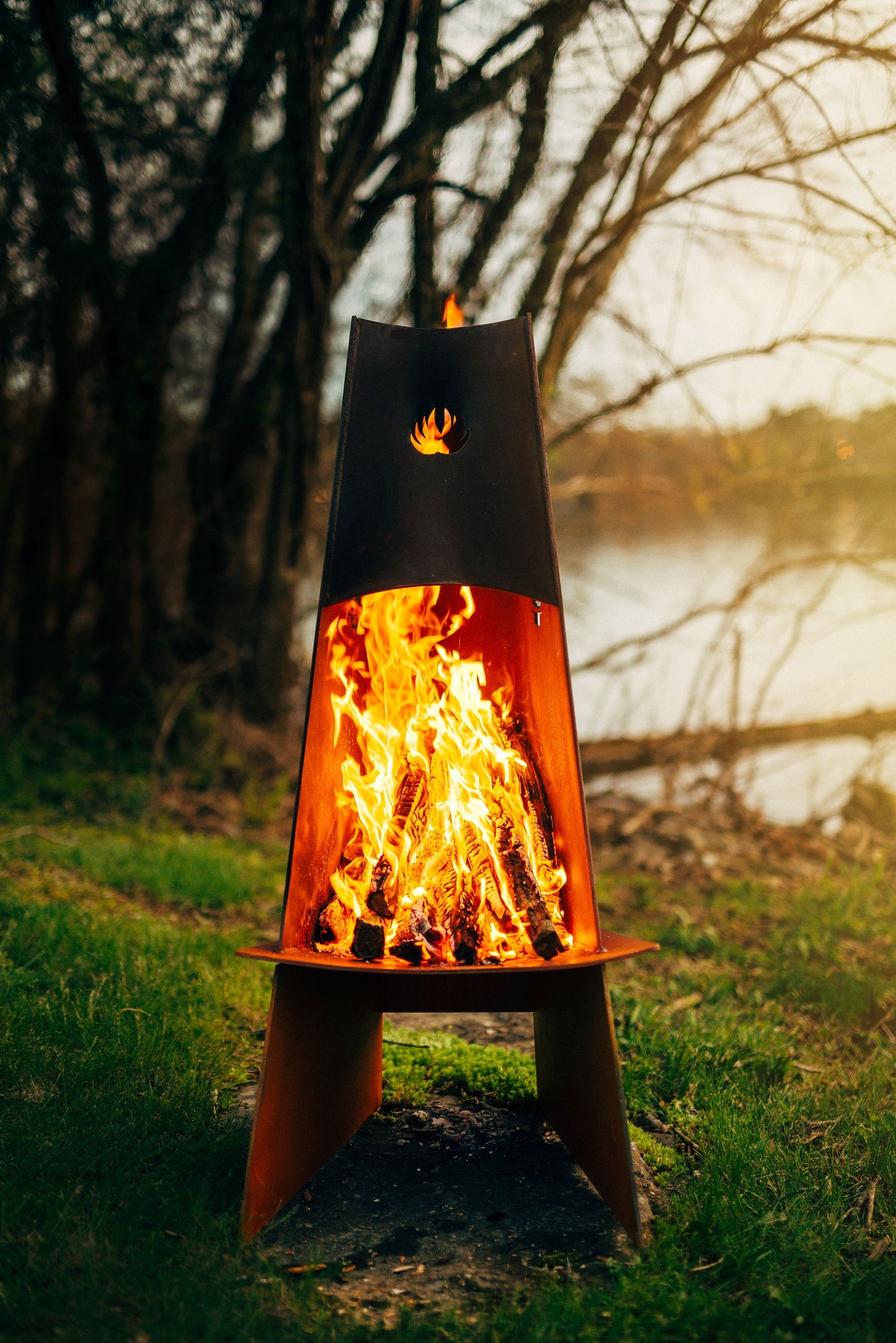 The Vesuvius wood burning fire pit, Displayed in a backyard, with a huge warm flame.