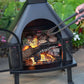 Black Wood Burning Outdoor Firehouse with Chimney & Cooking Grate being used to cook chicken and Steak.