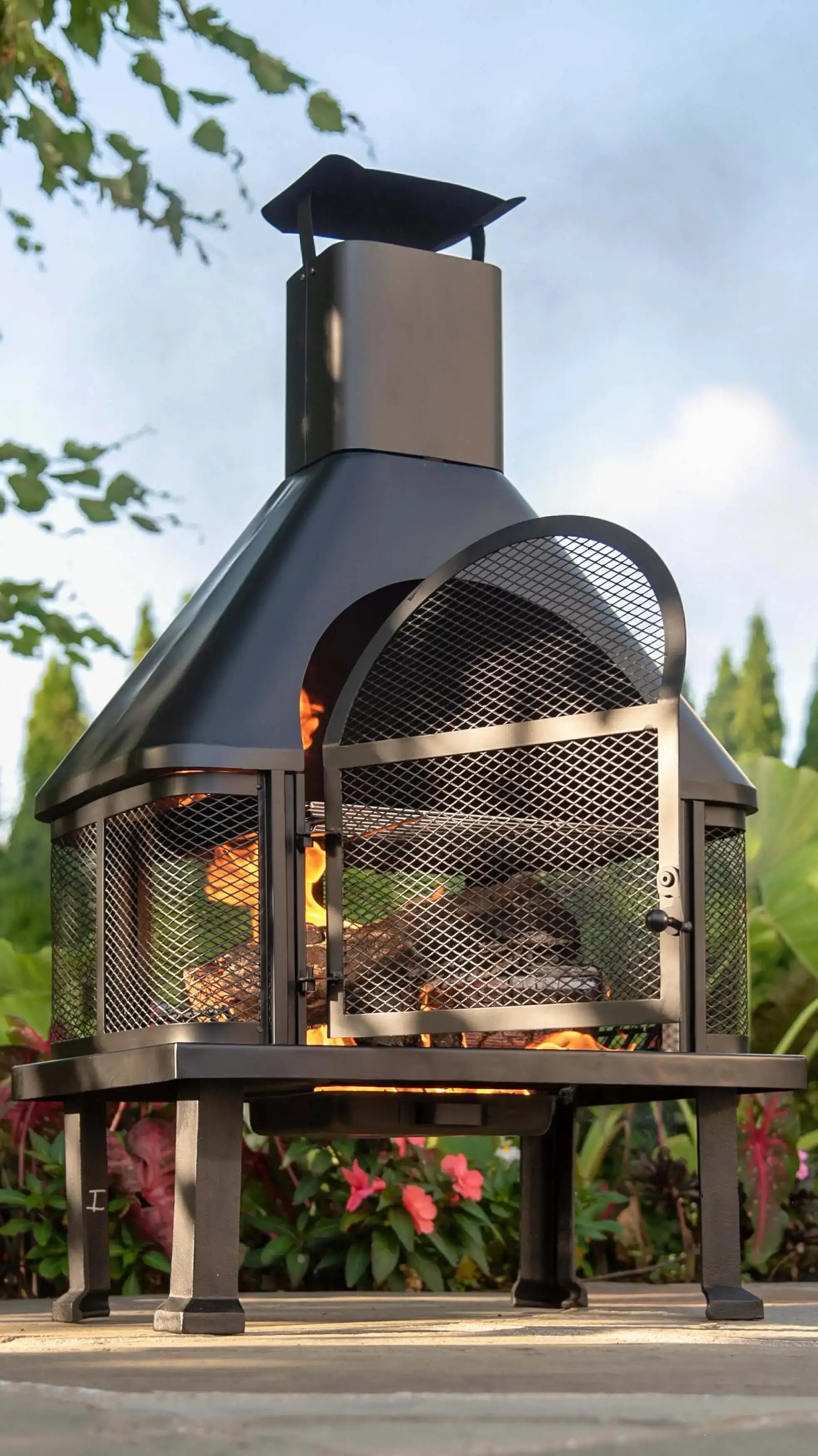 Black Wood Burning Outdoor Firehouse with Chimney & Cooking Grate with a open door, showcasing fire with warm flames,
