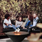 The Cairo Concrete Fire Bowl 01, being shown in a cozy setting, with family and friends gathered around the warm flame.
