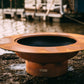 The stunning Magnum Fire Pit, Displayed on a lakeside rock.