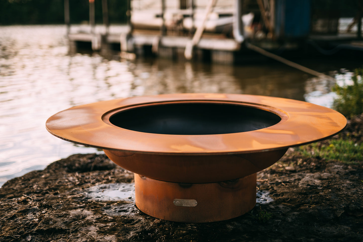 The stunning Magnum Fire Pit, Displayed on a lakeside rock.