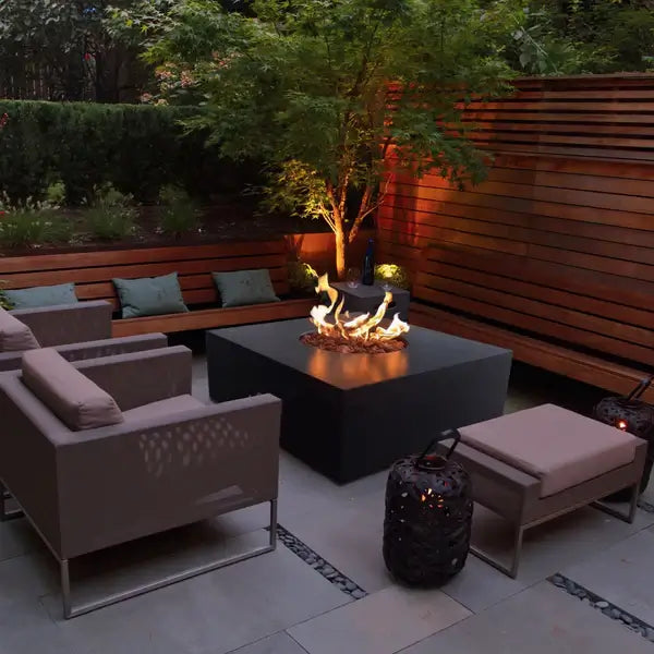 The elegant Praga Concrete Square Fire Pit, displayed in the Noir Color option in a backyard garden.