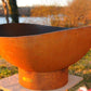 The Beautiful Scallop Fire Pit, displayed on a lakeside shore.