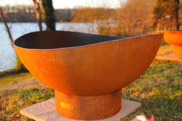 The Beautiful Scallop Fire Pit, displayed on a lakeside shore.