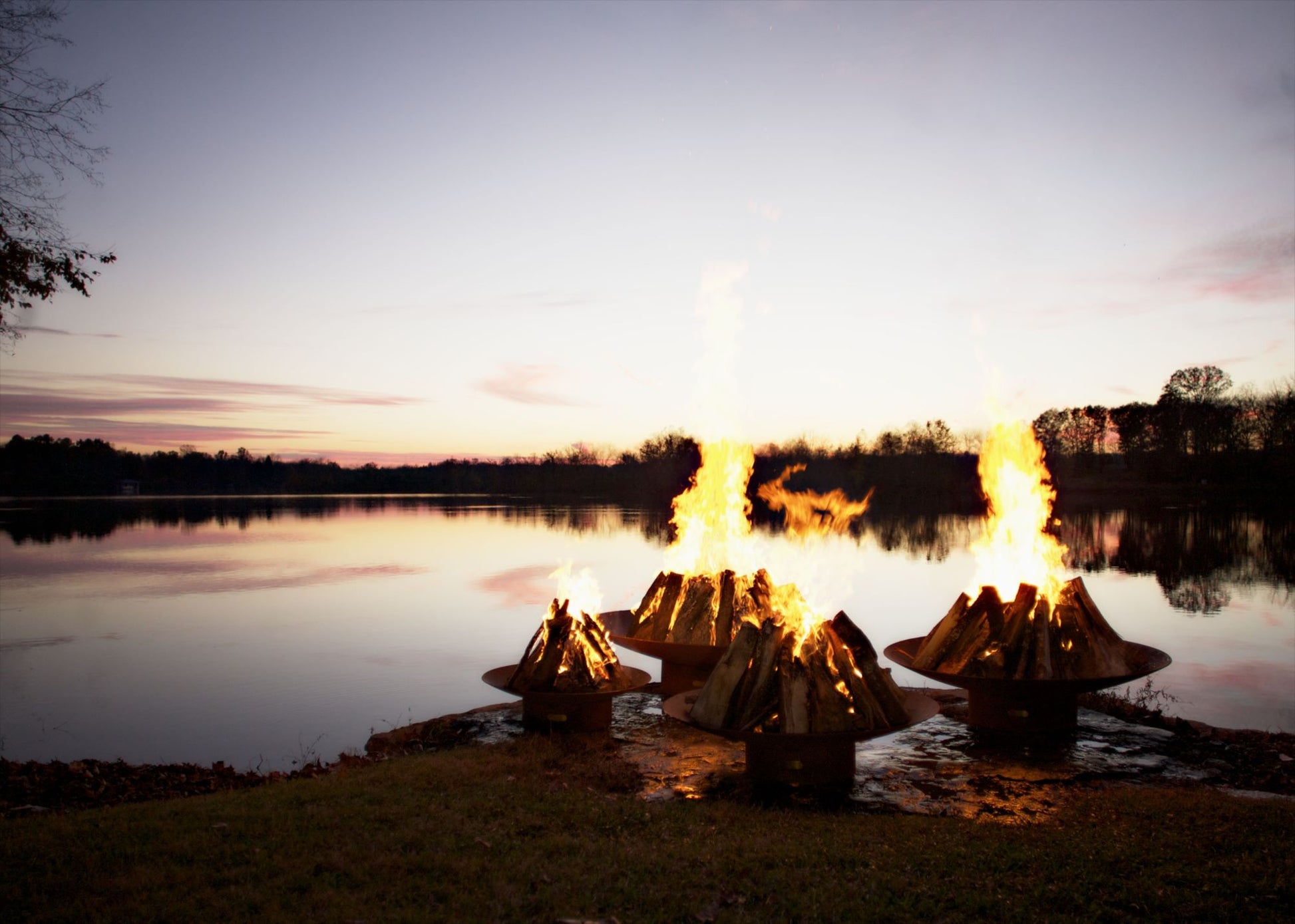 Asia Series oriental steel fire pit, showcasing all four size variants burning with a warm flame.
